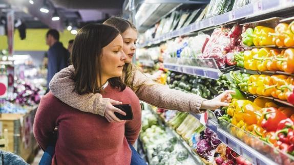 Mother and daughter in the supermarket looking at the vegetables